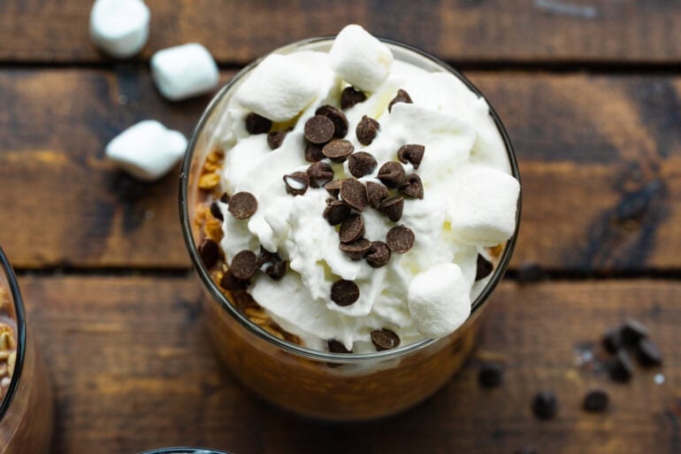 a small glass jar filled with chocolate overnight oats topped with whipped cream and sprinkled with mini chocolate chips
