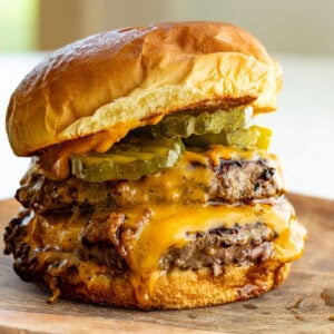 a perfectly grilled burger with two patties, melted cheese pickles and a toasted bun