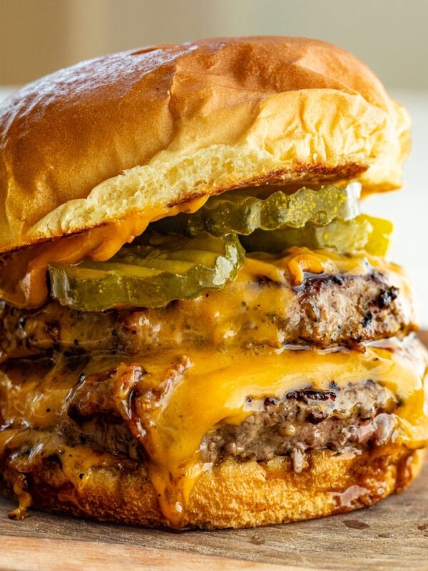 a perfectly grilled burger with two patties, melted cheese pickles and a toasted bun