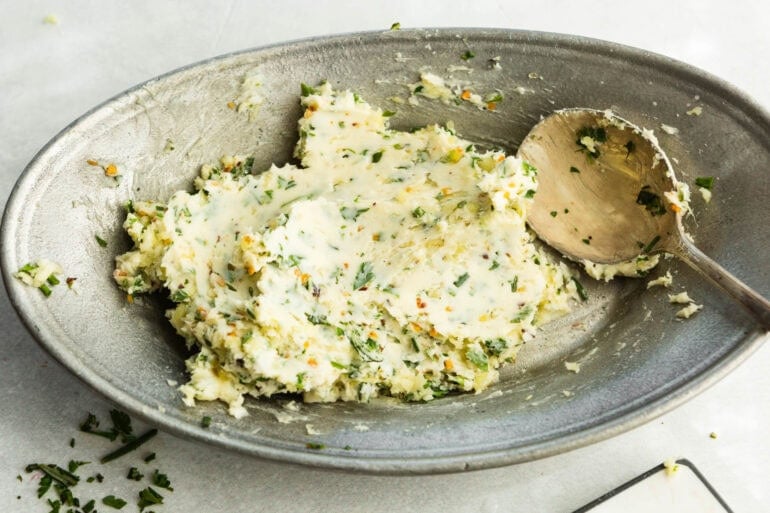 a wooden spoon mixing garlic butter in a shallow bowl