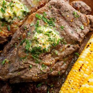 a grilled ribeye steak with a pat of garlic butter on top