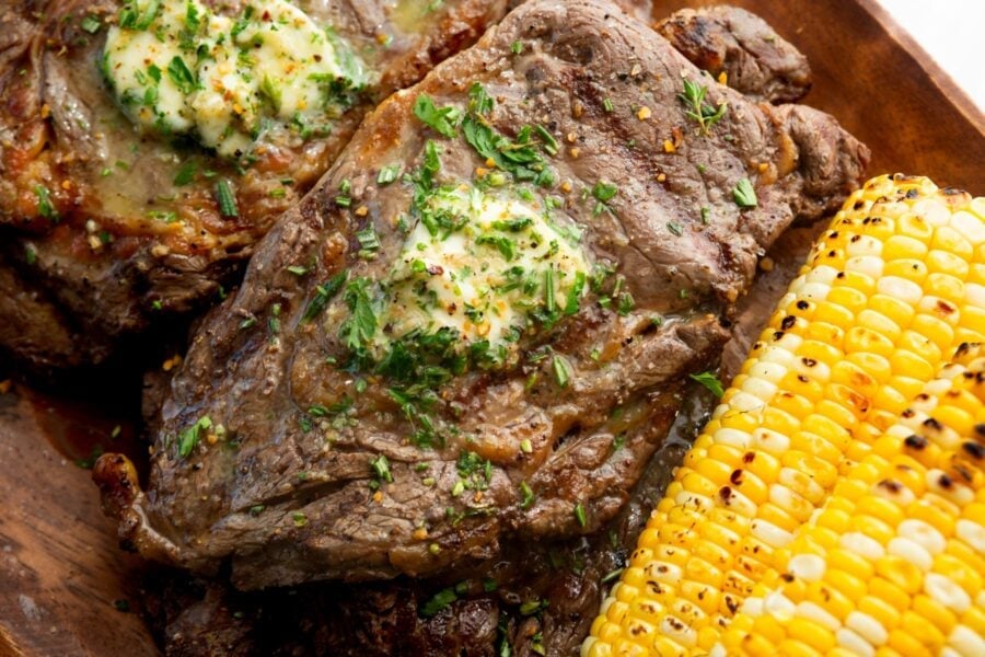 a grilled ribeye steak with a pat of garlic butter on top