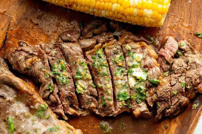 a large ribeye steak topped with garlic butter that has been grilled and is cut into slices