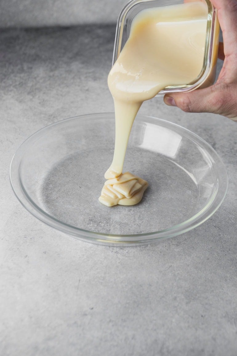 a photo if a can of sweetened condensed milk being poured into a glass pie plate