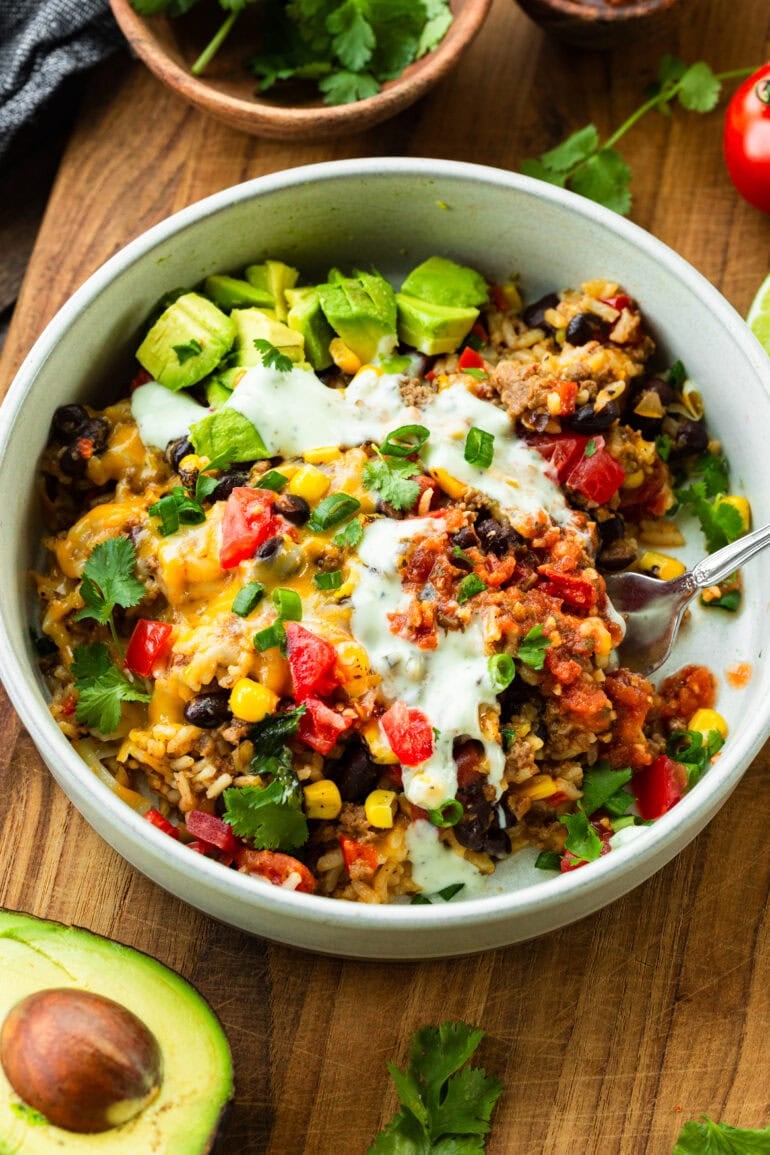 a ground beef burrito bowl topped with sour cream, avocados and chopped cilantro