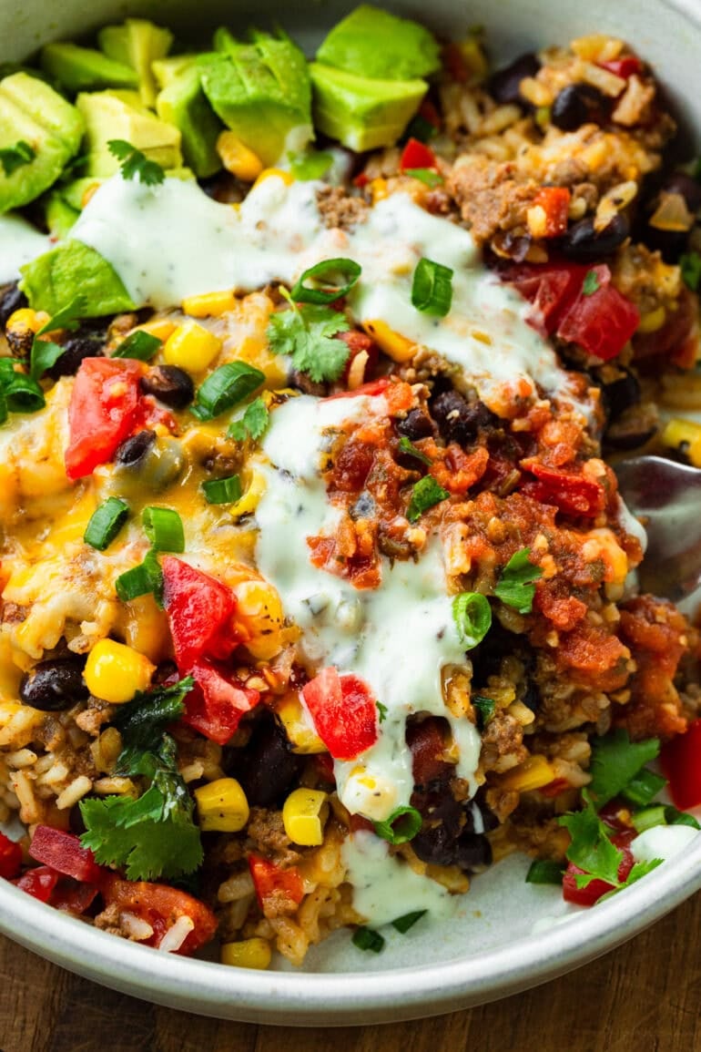 ground beef and rice burrito bowl topped with corn, diced tomatoes, sour cream and melted cheese
