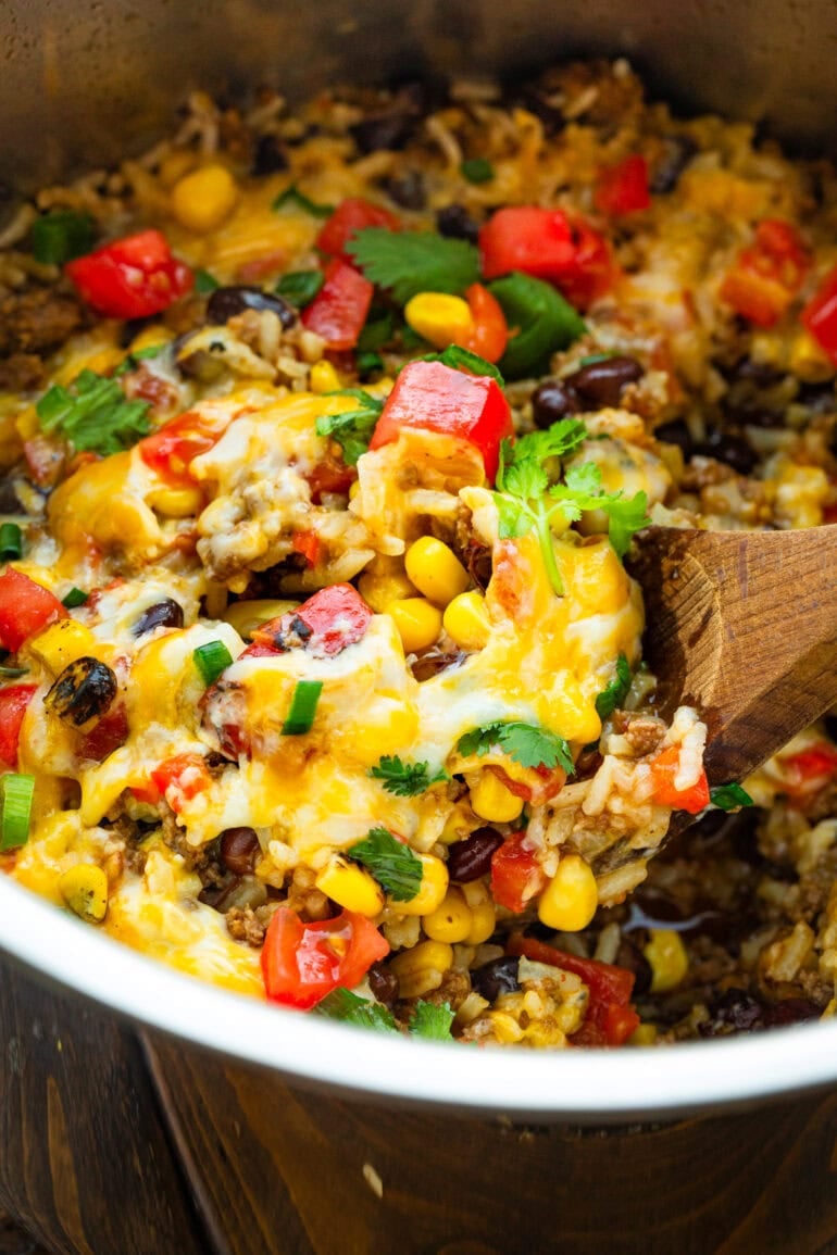 a wooden spoon scooping up a serving of ground beef burrito bowl