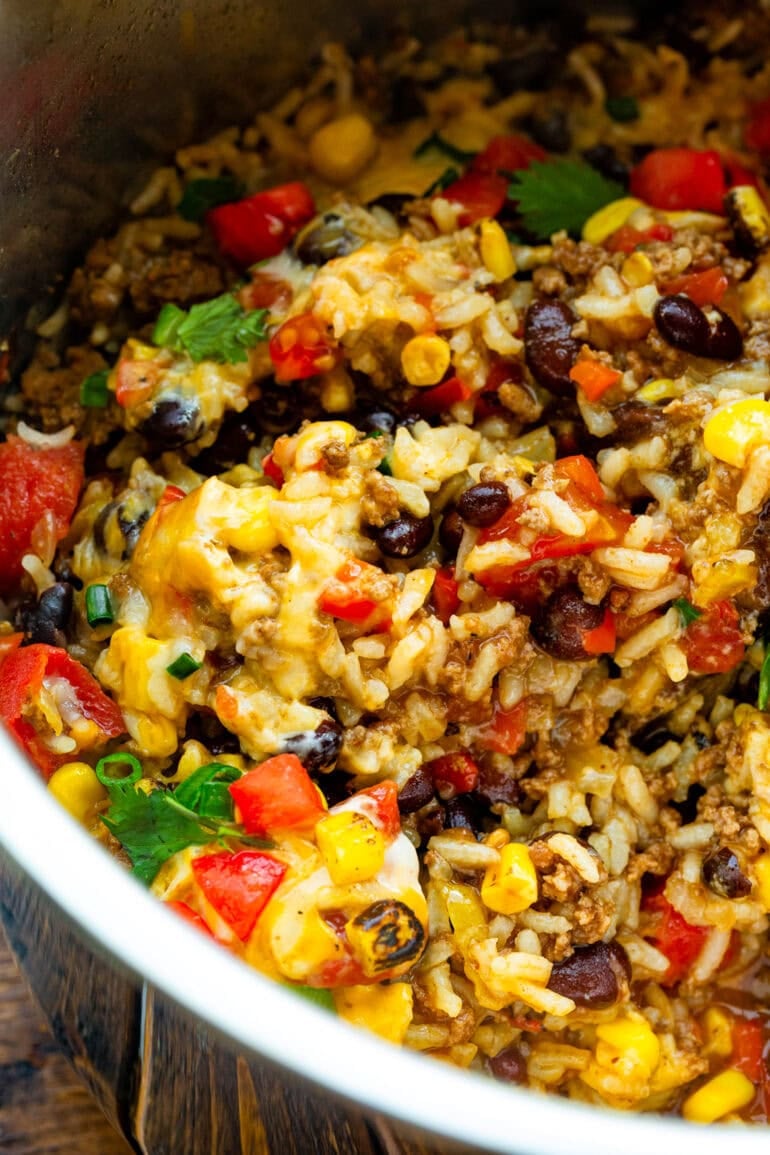a bowl of ground beef burrito bowl with rice, black beans, melted cheese, diced tomatoes, etc