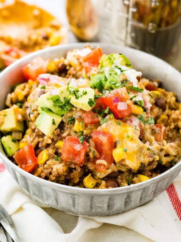 A photo of instant pot ground beef burrito bowl stopped with chopped tomatoes, avocado chunks, and chopped fresh cilantro.