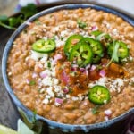 a bowl of instant pot refried beans with cheese, salsa, and jalapenos on top