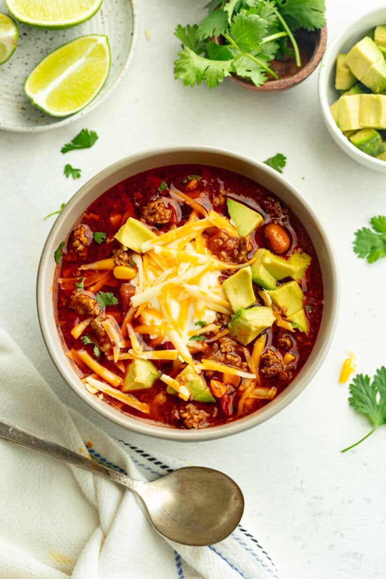 Grey bowl filled with mexican sopa, finished with fresh cilantro, creamy sour cream, shredded cheese, and avocado pieces.