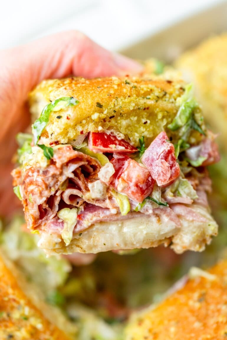 a photo of an italian slider sandwich loaded with sliced deli meats and chopped grinder salad