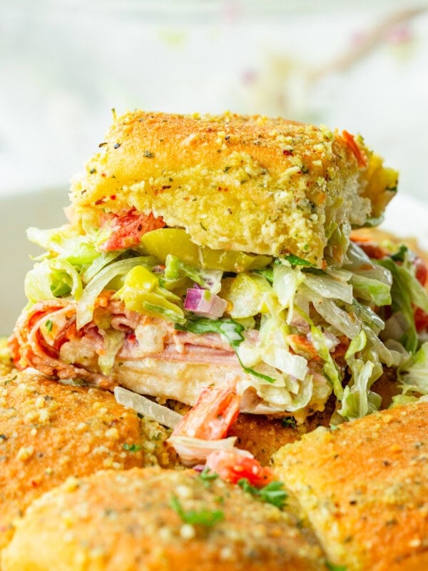 a photo of an italian slider on a golden bun loaded with lettuce, tomatoes, italian meats and a creamy italian dressing