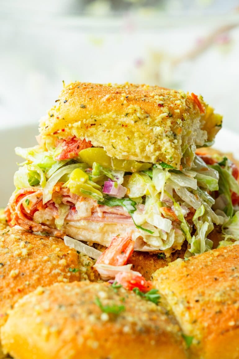 a photo of an italian slider on a golden bun loaded with lettuce, tomatoes, italian meats and a creamy italian dressing