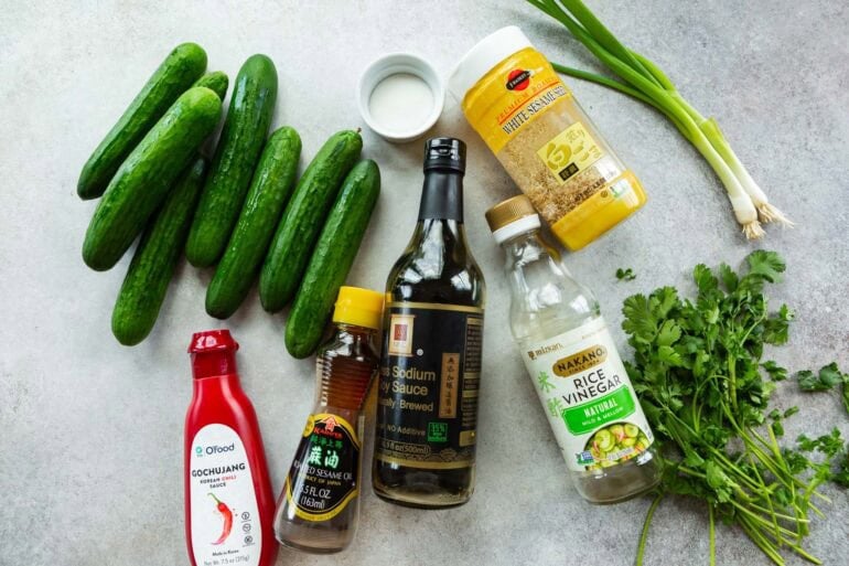 all the ingredients for Korean cucumber salad including cucumbers, soy sauce, sesame oil, cilantro, scallions and gochujang 