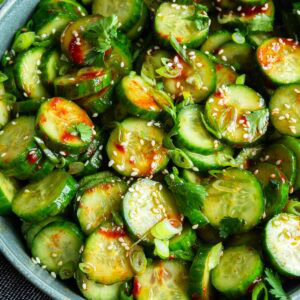 a large serving bowl of Korean cucumber salad topped with toasted sesame seeds and sliced green onions