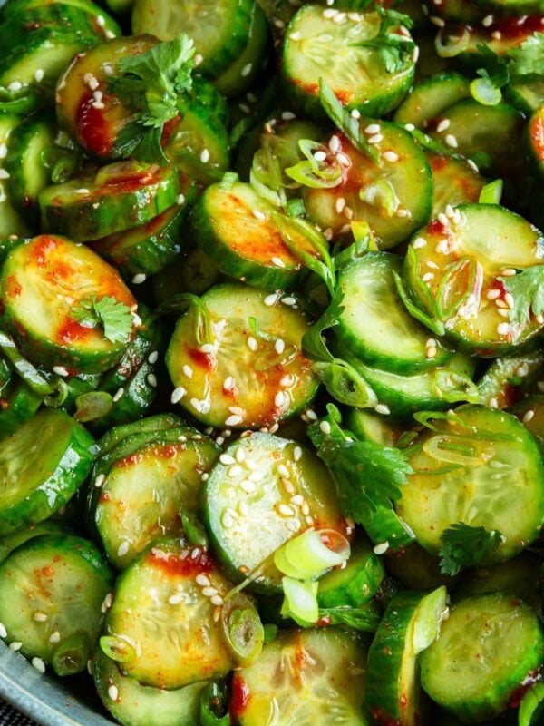 a large serving bowl of Korean cucumber salad topped with toasted sesame seeds and sliced green onions