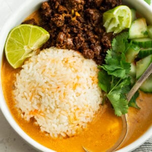 Overhead view of beef broth bowls with Korean ground beef, rice, cucumber, cilantro and lime