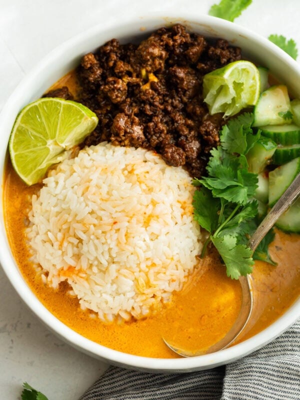 Overhead view of beef broth bowls with Korean ground beef, rice, cucumber, cilantro and lime