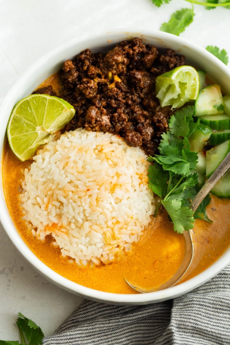 Overhead view of beef broth bowls with Korean ground beef, rice, cucumber, cilantro and lime