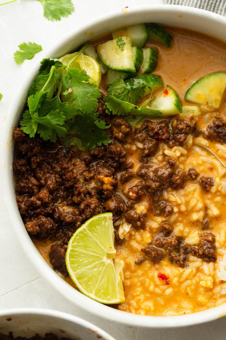 Korean beef broth bowl with crispy ground beef, white rice, cucumber, cilantro and creamy coconut gochujang broth