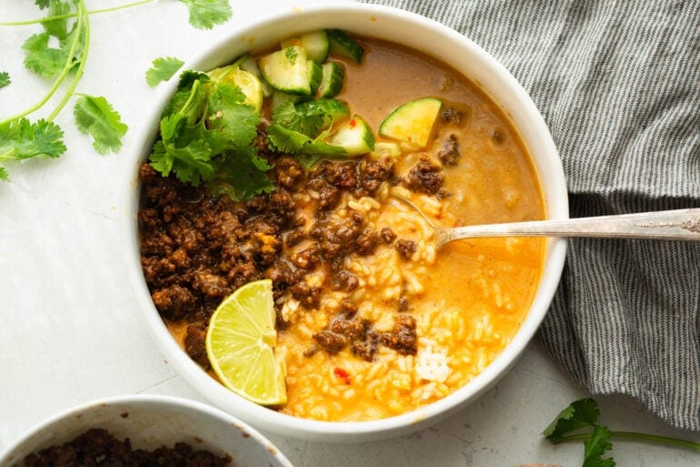Korean ground beef broth bowl topped with cucumber and cilantro with fresh lime wedges