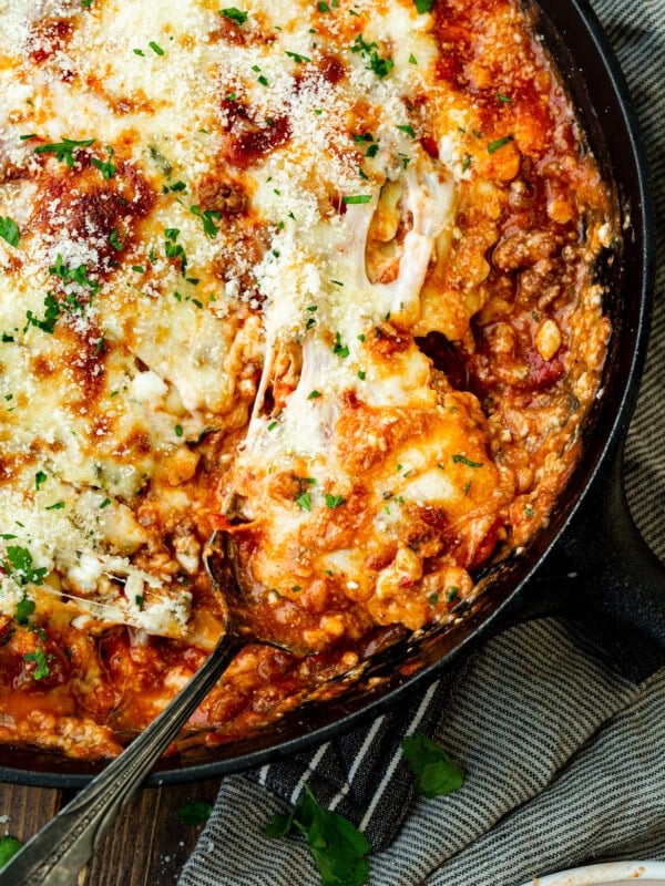 a photo of a serving of skillet lasagna being scooped out of a cast iron skillet