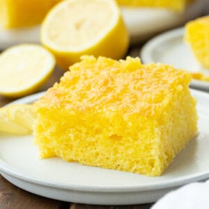 a photo of a piece of moist lemon jello cake sitting on a small white dessert plate