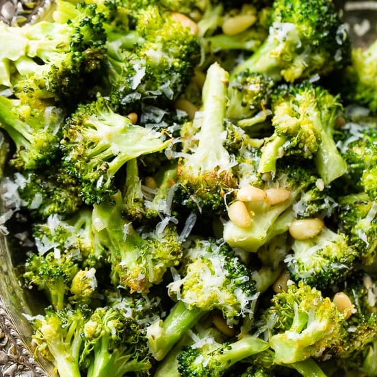 A close up of lemon roasted broccoli with pine nuts and parmesan cheese