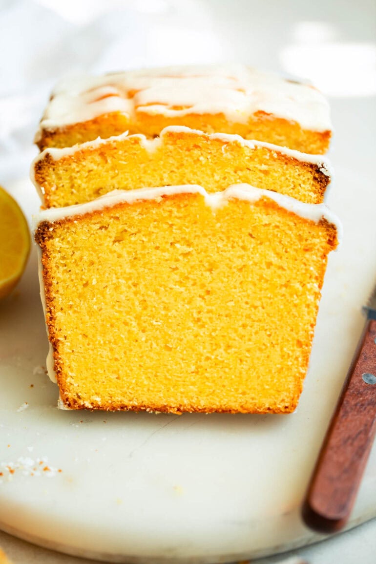 A photo of moist and dense lemon pound cake with white glaze