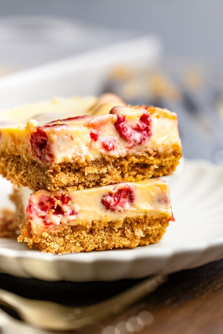 two creamy lemon raspberry bars with graham cracker crust stacked on each other on a small dessert plate
