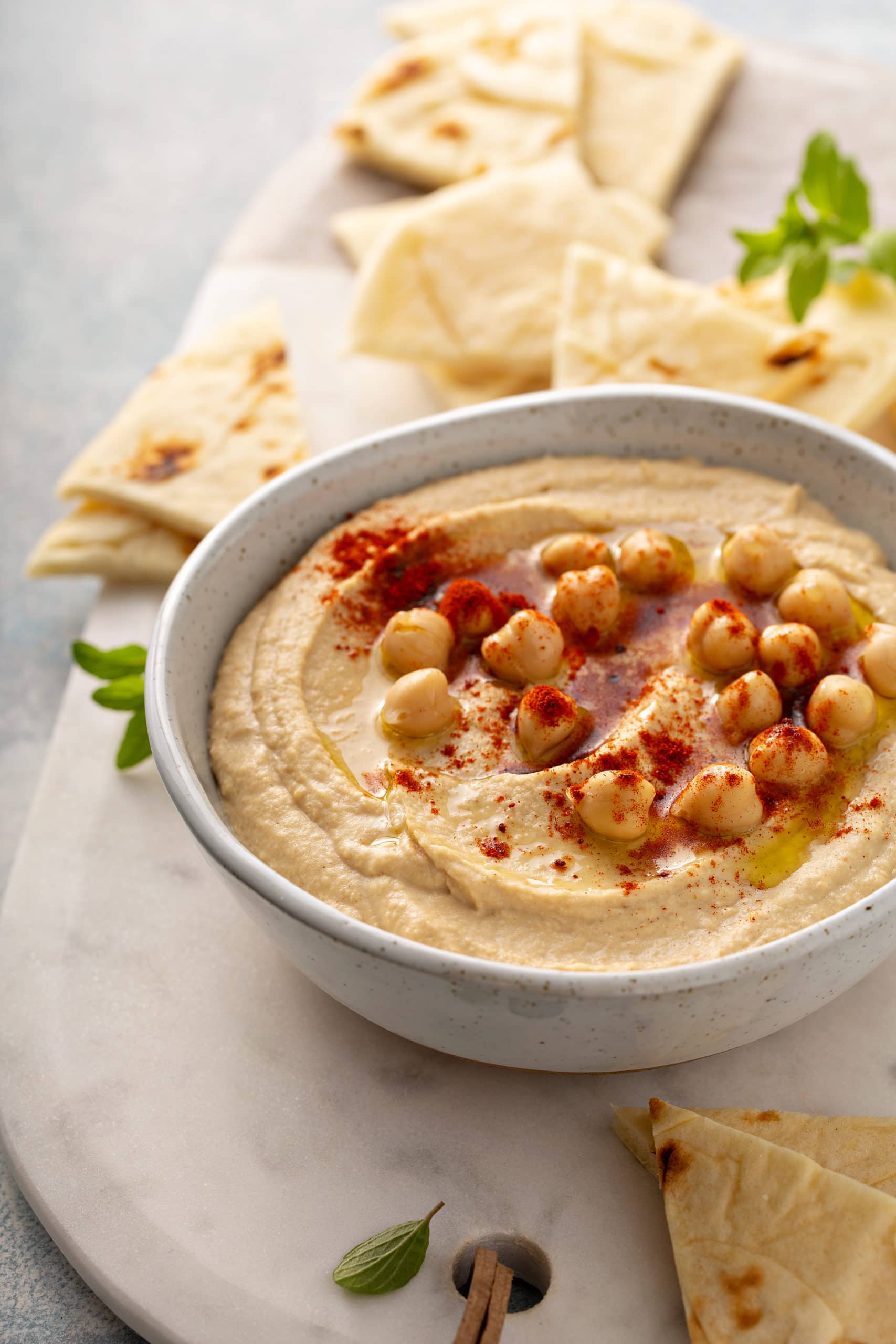 Best Easy Homemade Hummus Wedges of flour tortillas surrounding a bowl of hummus with whole chick peas on top, sprinkled with smoked paprika.
