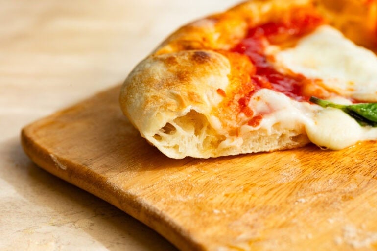 a slice of margherita pizza shown from the side to se the rise of the crust