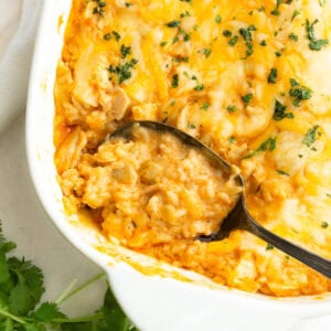 Spoon lifting a serving of creamy Mexican chicken and rice casserole from a baking dish
