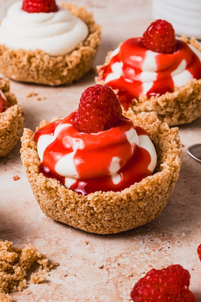 Creamy cream cheese filling nestled in a buttery graham cracker crust, finished with a drizzle of vibrant red berry sauce.