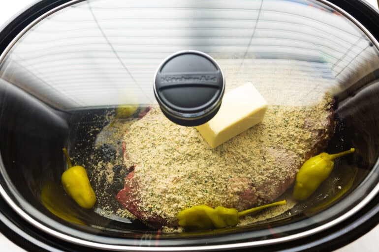 a slow cooker with all the ingredients for mississippi pot roast inside ready to cook with the lid on