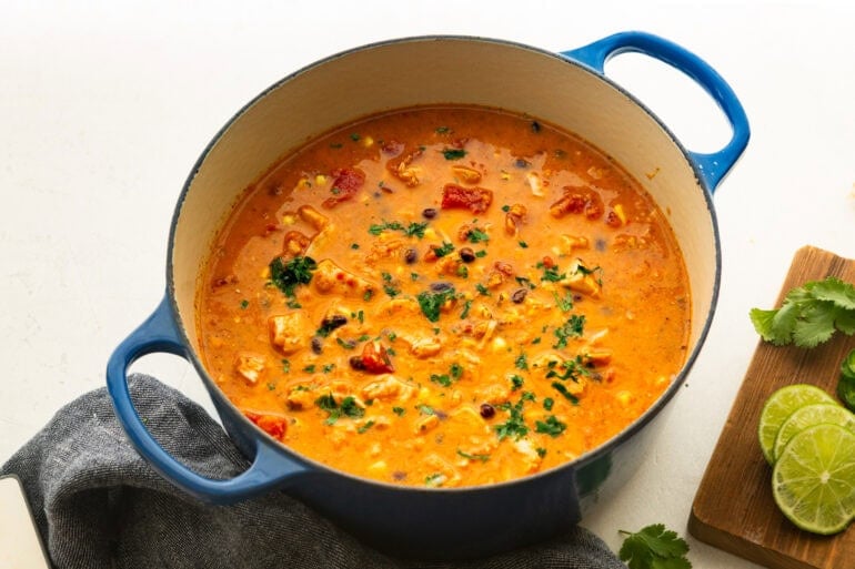 a large dutch oven pot full of chicken enchilada soup topped with a sprinkle of cilantro