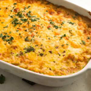 a golden baked chicken enchilada casserole topped with melted cheese and sprinkled with cilantro