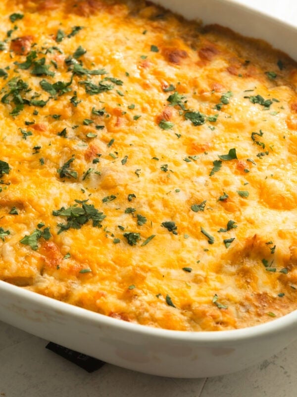 a golden baked chicken enchilada casserole topped with melted cheese and sprinkled with cilantro