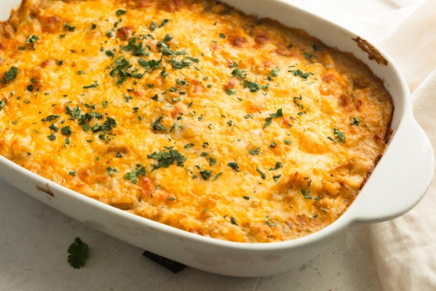 a golden baked chicken enchilada casserole topped with melted cheese and sprinkled with cilantro