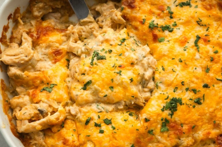 a spatula lifting a serving of chicken enchilada casserole from a casserole dish