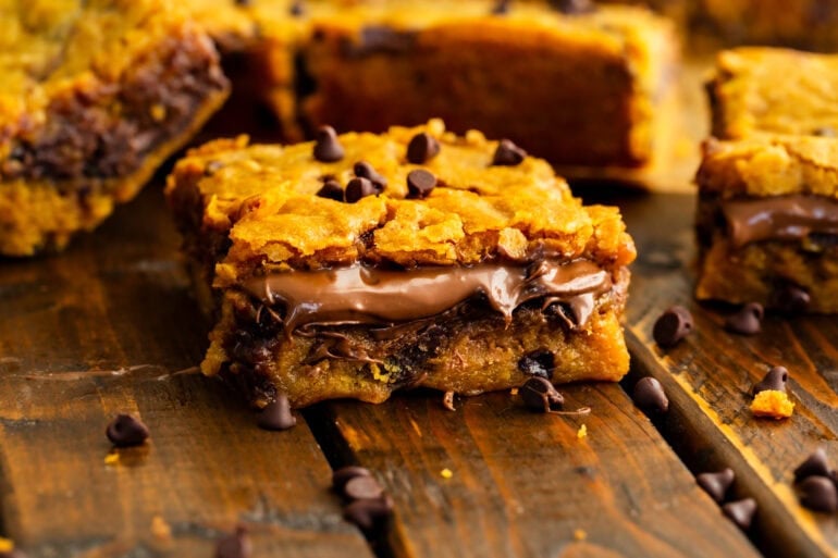A layered pumpkin chocolate chip dessert bar with a thick layer of nutella sandwiched between the layers.
