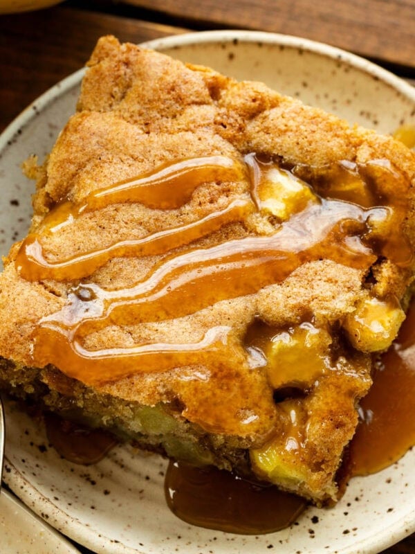 a slice of apple cake with caramelized top and warm caramel sauce drizzled on top