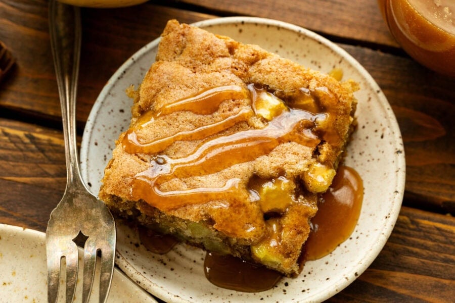 a slice of apple cake with caramelized top and warm caramel sauce drizzled on top