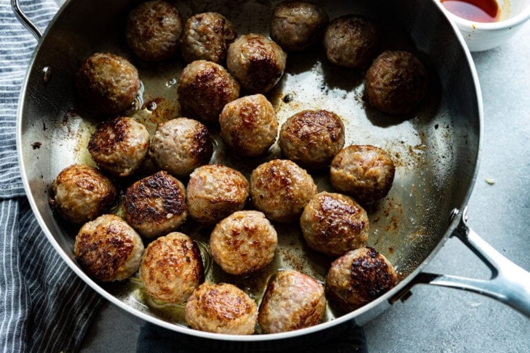 meatballs being browned in a large skillet