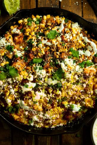 a photo of a cast iron skillet full of chunks of chicken mixed with creamy mexican street corn