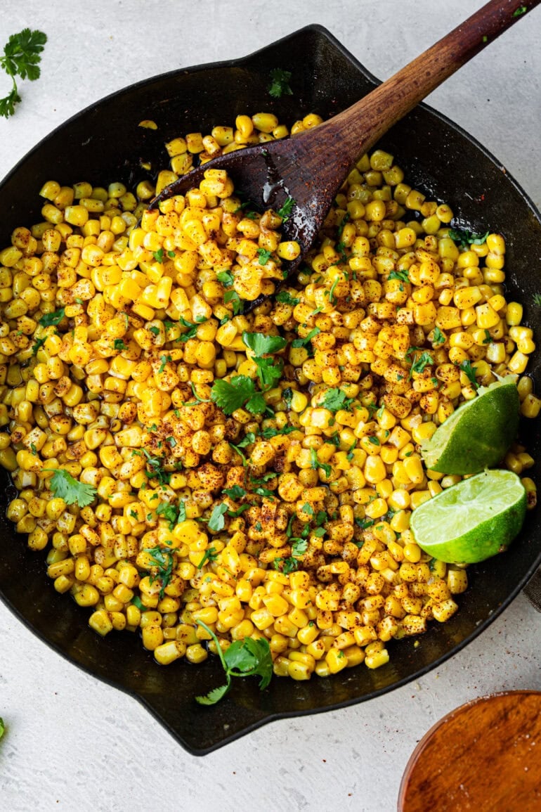 Cooked corn coated in glossy honey butter sauce, speckled with chili powder and flecks of lime zest.