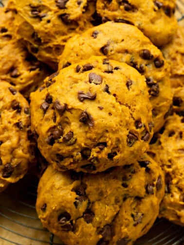 a photo of baked pumpkin chocolate chip cookies piled on top of each other