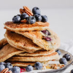 a stack of blueberry pecan pancakes with a drizzle of maple syrup