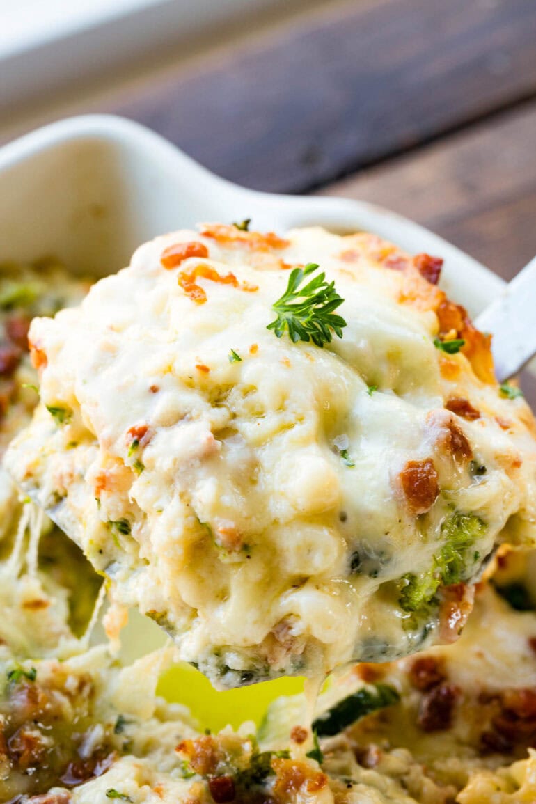 a photo of a scoop of creamy golden baked vegetable white lasagna being removed from a full pan of it 